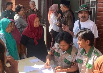 Tim PPK Ormawa HMP PTI UMS turut membantu mendistribusikan bantuan sosial pada warga Desa Seboto yang mengantre pembagian beras. Foto : Ist.